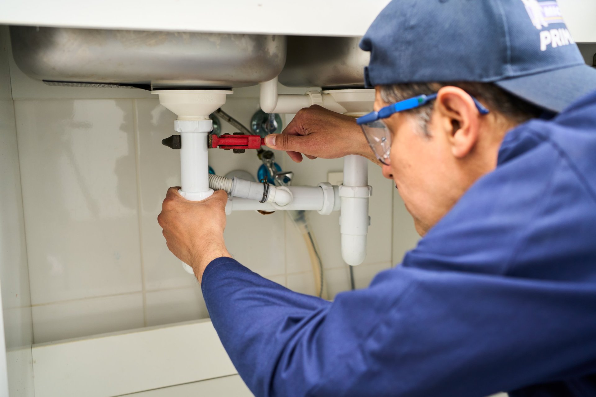 Professional plumber performing pipe repair in kitchen